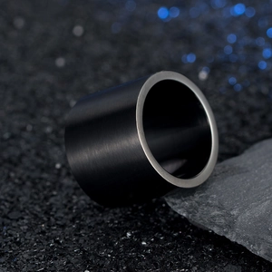 Matte black titanium wide band ring for men with polished edges on a dark stone background