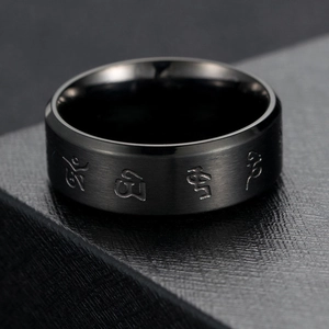 Macro shot of black brushed stainless steel ring with engraved religious mantra symbols
