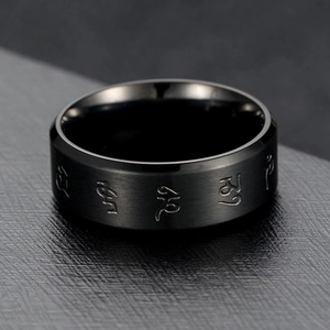 Macro shot of black brushed stainless steel ring with engraved Tibetan mantra symbols