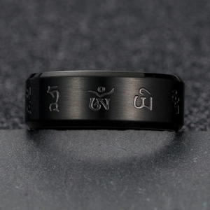Macro shot of black matte stainless steel ring with engraved Tibetan mantra symbols