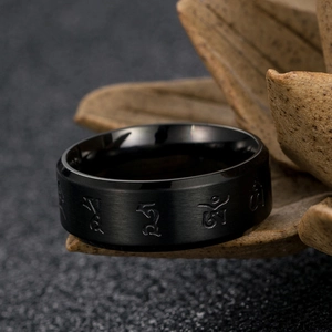Macro shot of black brushed stainless steel ring with Tibetan Six-Syllable Mantra carvings