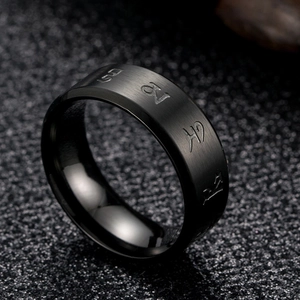 Detail of black brushed metal ring with engraved religious mantra and religious symbols