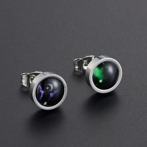 Macro shot of luminous constellation stud earrings with starry nebula glass in silver setting
