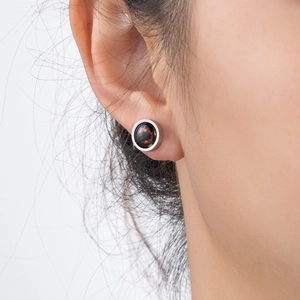 Detailed close-up of a stainless steel constellation stud earring on a male ear