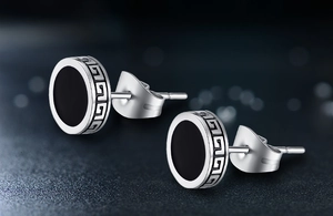 Macro detail of silver stud earrings with black inlay and Greek meander pattern edge