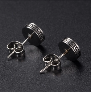 Close-up of black stud earring with Greek fret pattern and butterfly back closure