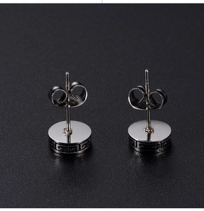 Macro shot of silver stud earring featuring geometric pattern and butterfly back closure