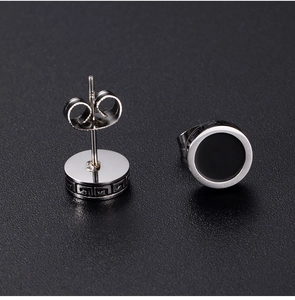 Close-up of silver hoop earrings with black inlay and Greek meander engraving patterns
