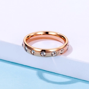 Polished rose gold stainless steel ring with circular clear crystals on white stand