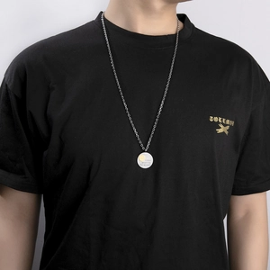 Collar con colgante de moneda de plata, sonrisa dorada y grabado sobre camiseta negra