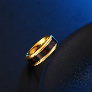 Dettaglio macro dell'anello in acciaio al titanio dorato con fascia nera e simboli buddisti