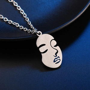 Minimalist silver abstract face pendant necklace with brushed metal finish on dark plate