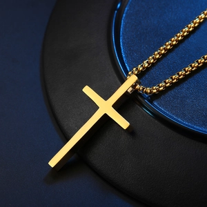Minimalist gold cross necklace for men featuring a box chain on a black textured base