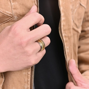 Détail d'une bague bicolore en acier inoxydable avec motif grec doré porté par un homme