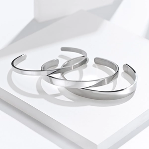 Minimalist silver stainless steel cuff bracelet set on a white geometric platform
