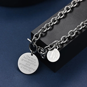 Détail des pendentifs gravés pour grand-mère et petite-fille sur une chaîne à maillons