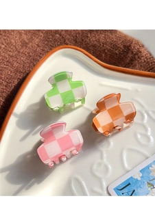 Close-up of three mini checkerboard hair clips in green, orange, and pink on a tray