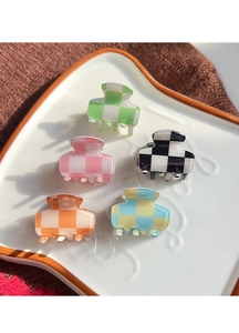 Detailed close-up of colorful checkered mini hair claws on a ceramic tray