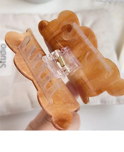 Close-up of amber marble resin hair claw clip with transparent spring and teeth