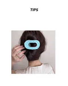 Dettaglio molletta per capelli ovale azzurra con motivo a rombi su capelli raccolti