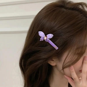 Elegant purple butterfly hair clip with sparkling rhinestones on long wavy brown hair