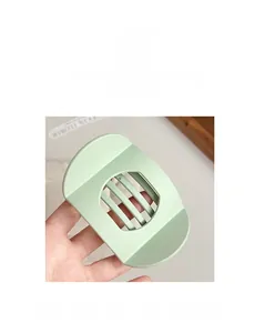 Détail d'une pince à cheveux vert menthe mate avec design rayé ajouré pour la coiffure