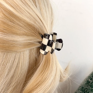 Chic black and white checkerboard hair claw clip styled on golden blonde hair