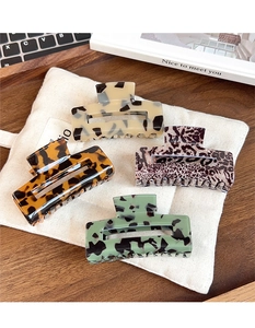 Detail of four leopard print acetate hair claws on a white fabric bag in a cozy setting