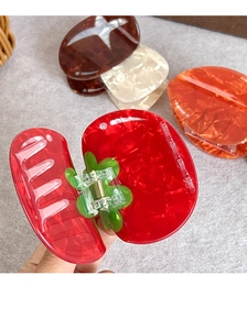 Makro-Detail einer tomatenförmigen Haarklammer und Acetat-Clips mit Marmorierung