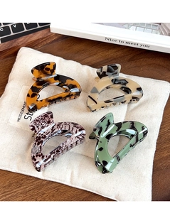 Set of four leopard print hair claws in tortoiseshell and marble patterns on a linen bag
