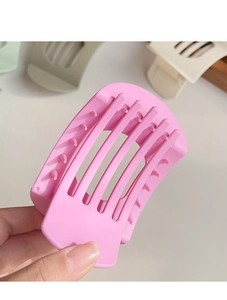 Détail d'une pince à cheveux rose au design incurvé ajouré avec des dents solides