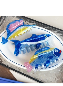 Detailed view of ocean-themed acetate fish hair claws with marble texture in a ceramic dish