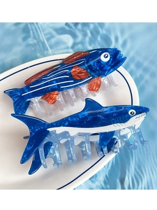 Macro view of blue sea creature hair claws with tuna and shark designs on ceramic plate