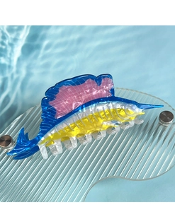 Detailed view of a colorful marlin fish hair claw clip on a rippling water surface