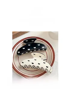 Detail view of large hair claws featuring cute dog patterns in black and creamy white resin
