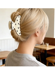 Detail of a large cream hair claw clip with black rabbit pattern on a woman's bun