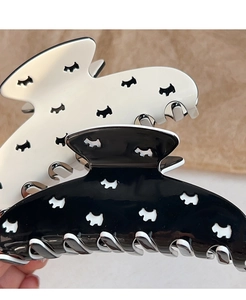 Detail shot of black and white hair claws featuring hollowed-out Scottie dog patterns