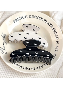 Detail of black and white hair claws with Scottie dog patterns on a ceramic plate