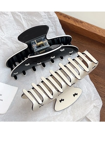 Detailed view of large resin hair claws featuring cute dog patterns in black and cream white