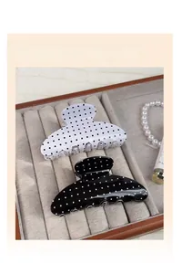 Detail of retro polka dot medium hair claw clips on a beige jewelry display tray
