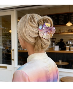 Vue détaillée d'une pince à cheveux fleur holographique sur un chignon élégant