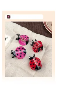 Detail of ladybug hair clips in red and pink acetate with polished black polka dots