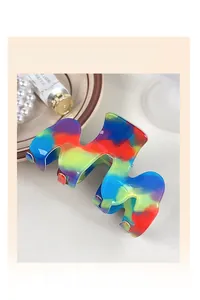Vista macro dettagliata della molletta geometrica a onde in resina con finitura arcobaleno vivace