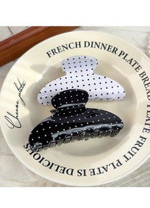 Close-up of retro black and white polka dot hair claws on a vintage ceramic plate