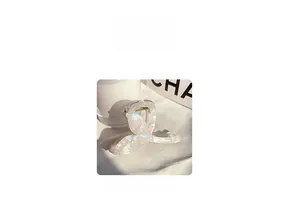 Detail view of pearlescent white mermaid tail hair claw clip with elegant metallic spring