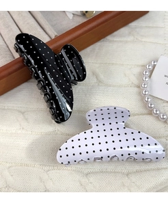 Detailed view of medium black and white polka dot hair claws on a warm cozy setting