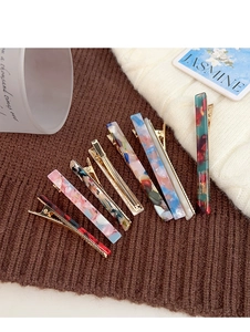 Detailed view of tortoiseshell acetate hair clips with various marble patterns and gold metal clips