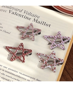 Detail view of four star-shaped hair clips with leopard, plaid and polka dot patterns