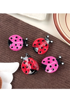Set of four red and pink ladybug acetate hair clips displayed on brown velvet fabric