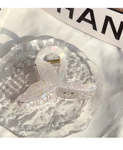 Detailed view of an iridescent mermaid tail hair claw with pearly white finish